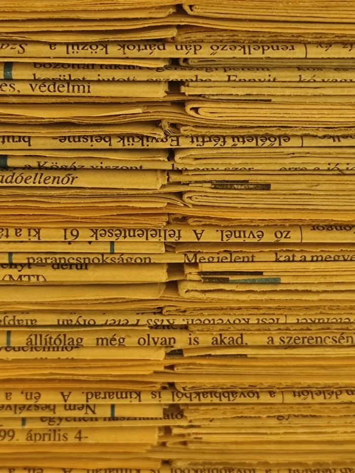 Close-up view of stacked vintage newspapers with yellowed pages and readable text.